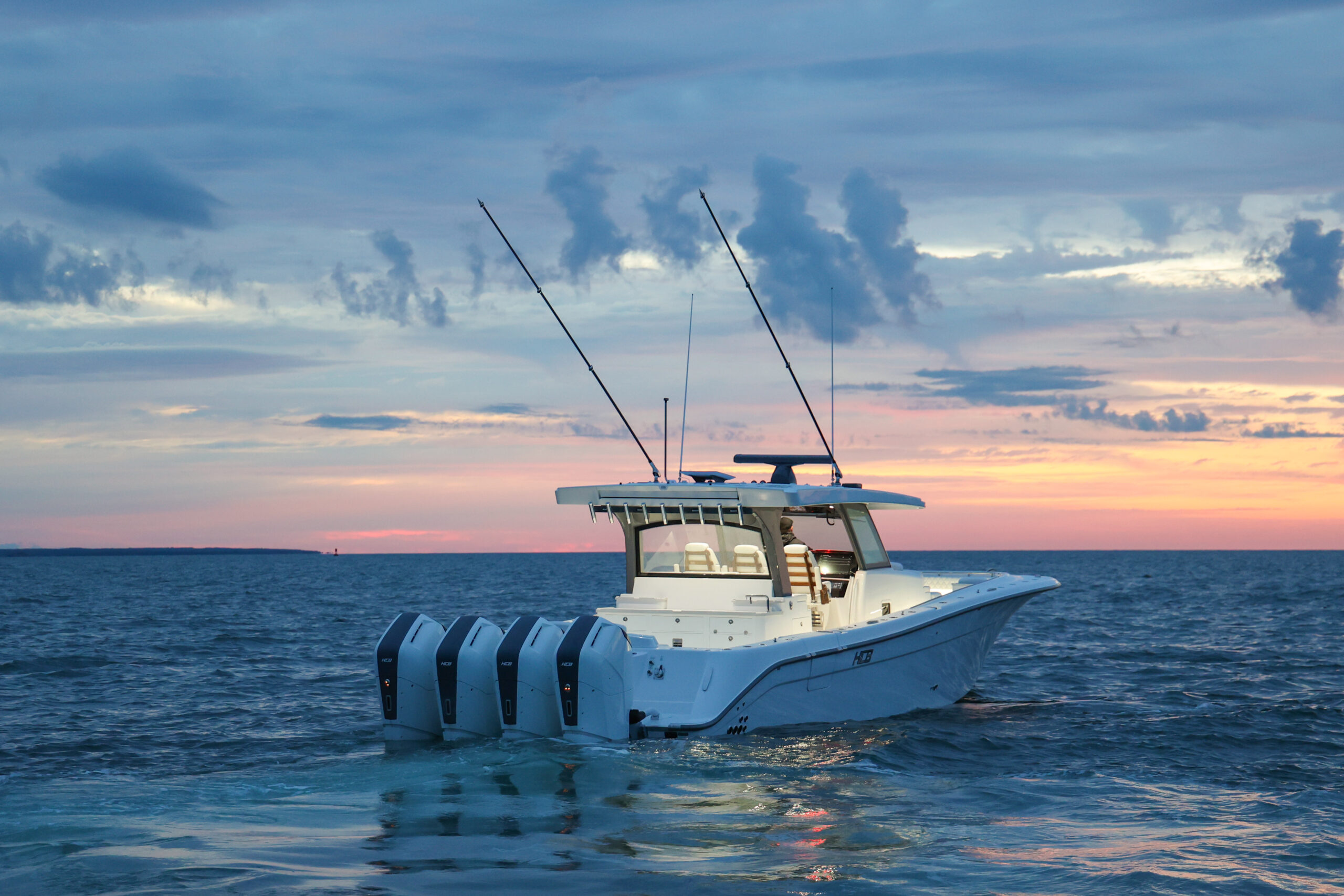 Center console with quad outboards idling offshore at sunset